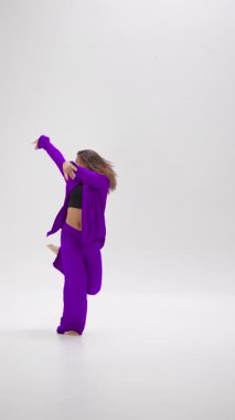 Zarif bir çıplak ayaklı dansçı, renk değiştiren kıyafetlerde akıcı bir performans sergiler. Minimalist beyaz odaya canlı bir enerji katar.