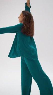 Renk değiştiren kıyafetli zarif bir dansçı, minimalist beyaz bir arkaplan karşısında pürüzsüz, akıcı hareketler yapar. Dans ve kıyafetin renkleri arasındaki dinamik etkileşimi gösterir.