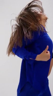 Zarif bir genç dansçı, temiz, minimalist beyaz bir stüdyo tarafından çerçevelenmiş renk değiştiren bir kostüm giyer.