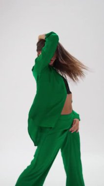 Etkileyici genç bir dansçı, ısıya duyarlı giysiler içinde zarif bir şekilde hareket eder, dinamik koreografisini temiz, minimalist bir stüdyo ortamında sergiler.