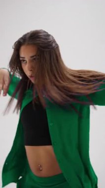 Genç bir kız canlı, renk değiştiren bir kıyafetle zarif bir şekilde dans ediyor. Minimalist beyaz bir stüdyoda sıvı hareketleri sergiliyor.