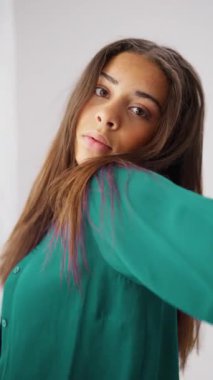 Genç bir bayan dansçı, minimalist beyaz bir stüdyoda akıcı el hareketleri ile duygularını zarifçe ifade eder.