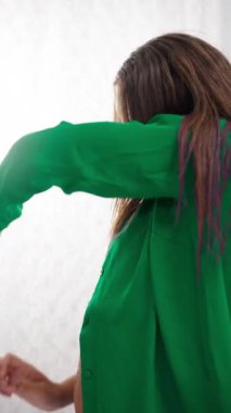 Yeşil kıyafetli modern dansçı, parlak, minimalist bir stüdyoda, yumuşak kumaş etkileşimiyle sıvı hareketini harmanlayan saf beyaz perdesiyle zarifçe hareket eder.