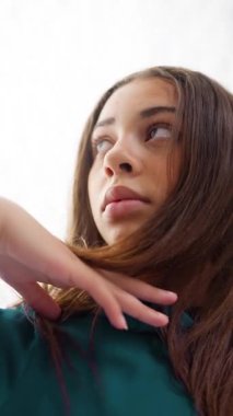 Mavi elbiseli genç bir dansçının temiz beyaz bir stüdyo arkaplanına nazikçe poz verdiği yakın plan bir fotoğraf.