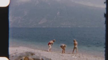 8mm 'lik klasik görüntülerde kardeşler, Garda Gölü' nde sakin bir günün tadını çıkarırken temiz suya taş atıyorlar.