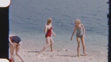 Mayolu genç kadınlar, güneşli bir günde Garda Gölü 'nün berrak sularına taş atarak neşeli bir anın tadını çıkarıyorlar. Eski bir nostaljik film tarzında yakalandılar.