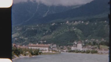 Eski bir 8 mm 'lik film, bereketli dağların çerçevelediği sakin bir göl manzarasını yakalıyor, zamansız ve nostaljik bir atmosferi çağrıştırıyor.