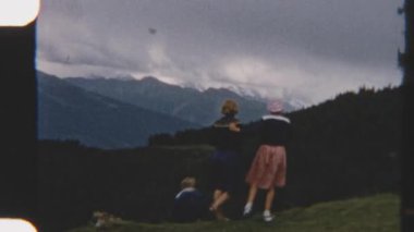 Eski bir 8 mm 'lik film, sakin bir yamaçta toplanmış bir aileyi yakındaki dağların nefes kesici panoramik manzarasının tadını çıkarırken yakalıyor.