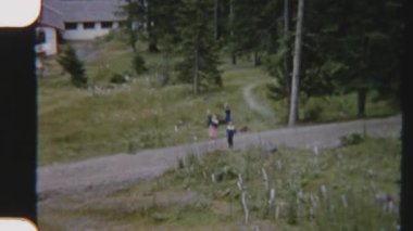 8mm 'lik klasik film tarzı POV, bir teleferikte kardeşler kameraya doğal yeşilliklerle çevrili bir şekilde mutlu bir şekilde el sallıyor.