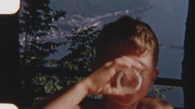 Klasik 8 mm 'lik, nefes kesici göl kenarı ve dağ zeminiyle içki içen genç bir çocuğun zamansız bir sükunet anını yakaladığı görüntüler.