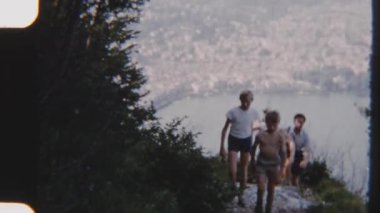 8mm 'lik klasik bir aile görüntüsü, sakin bir göl manzarası olan patika boyunca boş boş yürürken, zamanda huzurlu bir anı yakalıyor.