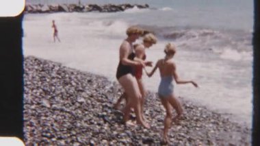 Engebeli bir kıyı şeridinde dikkatli bir şekilde seyreden bir ailenin 8mm 'lik klasik görüntüleri. Güçlü dalgalar kayalık kıyı şeridine çarpıyor.