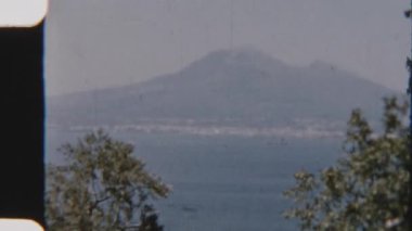 Tahıllı 8 mm 'lik görüntüler Napoli Körfezi' nin üzerinde beliren görkemli Vezüv Dağı 'nı yakalıyor ve İtalya' nın en ikonik manzaralarından birinin nostaljik ve zamansız bir görüntüsünü anımsatıyor.