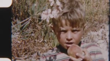 Genç bir çocuk sulu, taze bir şeftaliyi ısırıyor, güneşli havanın tadını çıkarıyor.