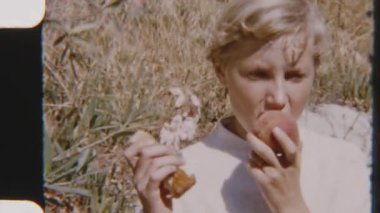 Genç bir kız, güneşli bir açık havada olgun bir şeftalinin tadını çıkarıyor. Sıcak bir günde taze meyvenin tadını çıkarıyor.