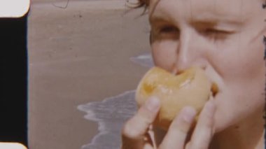 Arka planda Terracina Sahili 'nin yumuşak okyanus dalgalarıyla taze şeftalinin tadını çıkaran bir kızın yakın çekimi.