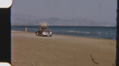 Klasik bir VW Beetle, 8mm 'lik nostaljik klasik bir filmle çekilen kumlu Terracina kıyılarında dolaşır.