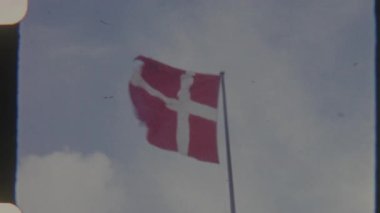 8 mm 'lik film görüntüleri Danimarka bayrağının hareket halindeki halinin arka planda berrak bir gökyüzü dalgalanması klasik, nostaljik bir hissi uyandırıyor.