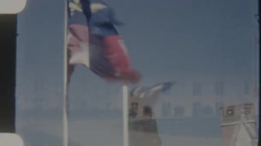 Karmaşık amblemli sembolik bir kraliyet bayrağı, açık mavi gökyüzü altında zarif bir şekilde dalgalanır, gelenek ve gücü simgeler.