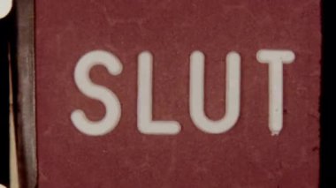 8mm film showcasing the word Slut as it spells out letter by letter against a vibrant red background, capturing a vintage and retro aesthetic