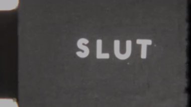 Vintage film ending featuring the word Slut in white text on a solid black backdrop, capturing a classic retro style with grainy 8mm footage