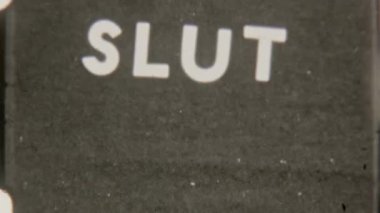 Retro 8mm film footage featuring bold, all-caps Slut text on a grainy black background, capturing a nostalgic and gritty vintage look