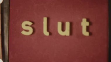 Grainy 8mm footage featuring the word Slut in small caps, set against a bold red background, offering a vintage, retro film style