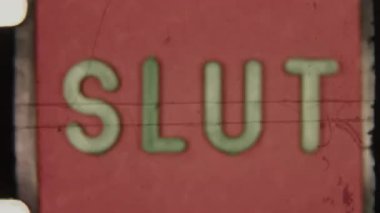 Retro 8mm film ending with the word Slut flickering on a red screen, accompanied by black film particles and vintage grain