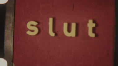 Vintage 8mm film showcasing the word Slut in lowercase text against a bold red backdrop with a classic analog feel