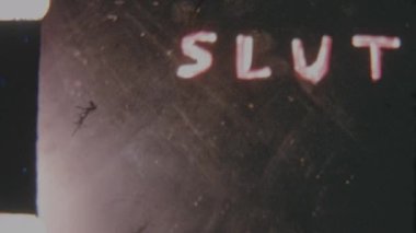A retro 8mm film effect featuring the bold word slut in white text on a solid black background