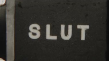 Classic analog 8mm film featuring the word Slut in bold all-caps typography on a textured black background with vintage film grain
