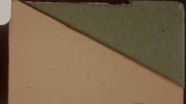 Klasik analog estetiği çağrıştıran, klasik bir görüntü yönetmeni logosunu gösteren kırmızı şeritli 8 mm film geçişleri