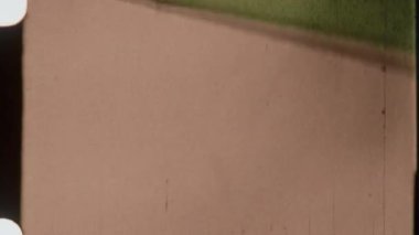 Kumlu bir 8 mm film efekti, klasik bir sinematografi logosunun yer aldığı canlı kırmızı bir film şeridine sorunsuzca dönüşür.