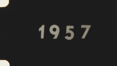 8mm film lideri 1957 tarihini görünür çıkıntı delikleri, titreşim ve klasik film tahıllarıyla gösteriyor.