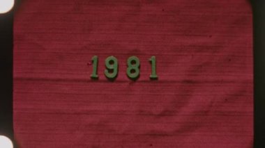 Orijinal 8 mm 'lik film çerçevesi 1981 yılına özgün kırmızı bir arkaplanda yaklaşarak nostaljik ve geçmişe dönük bir görüntü yakalıyor.