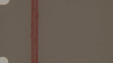 Eski bir 8 mm film lideri soluk bej arka planda kırmızı dikey bir çizgi çizer, görünür toz, çizikler ve hafif yanık izleri ile nostaljik olarak özgün bir retro estetik ideal yaratır.