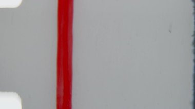 Soluk bir dikey kırmızı çizgi ve eşlik eden metin, küçük kusurlar ve görünür tahılların yer aldığı sessiz bir arkaplan üzerine yerleştirilmiş 8 mm 'lik ön rulo klibinin sol kenarı boyunca konumlandırılmıştır.