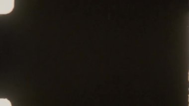 Dikey çizikler, toz parçacıkları ve kenar yanıkları olan koyu bir çerçeve içeren otantik 8mm film şeridi