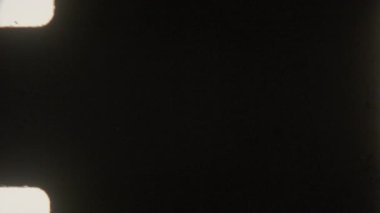 Otantik 8 mm film, hafif ışık yanıkları, yanıp sönen kenarları, görünür çerçeve çizgileri, organik kusurları ve koyu renkten açık griye düzgün bir değişim içeren koyu, kumlu görüntüler içerir.