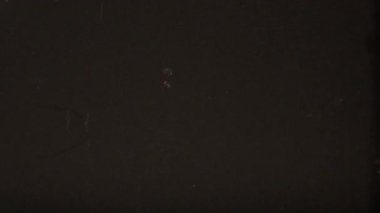 Eski bir 8 mm 'lik koyu renk film, doğal hasarı taklit etmek için koyu kahverengi-siyah yüzey boyunca uzanan hafif dikey çizikler ve kavisli sıyrıklarla yıpranmış ve yıpranmış bir dokuyu barındırır.