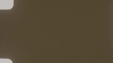 Kenarları boyunca karakteristik deliklerle örtüşen 8 mm 'lik bir film, kahverengi renkli ve dağınık koyu benekli boş bir çerçeve sergiliyor.