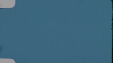 Bu mavi 8 mm 'lik film yumuşak, soluk bir dokuyu hafifçe eğri büğrü, ince kenar delikleriyle ve dağınık toz zerreleri ve sıkıntılı retro' sunu güçlendiren hafif çiziklerle kaplar.