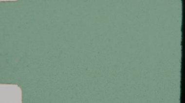 Özgün bir retro estetik serpiştiren, dekolteli kenarlar, eski film makaralarına ikonik, dokulu yüzey çizikleri, lekeler ve kusurlar içeren yeşil bir film kaplaması.