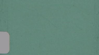 Dokulu bir film, kısmen görünür beyaz bir dikdörtgen iken, yaş ve aşınmayı çağrıştıran dağınık benekler ve işaretler ile baskın yeşil renk ile örtüşür