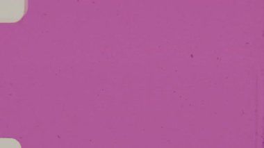 İnce toz, tahıl ve çizik izleriyle kaplı, özgün bir vintage projektör estetiği için yuvarlak çerçeve kenarları ve görünür deliklerle kaplı, Retro-style Pembe 8mm film.