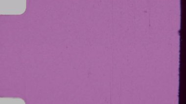 Açık pembe 8 mm 'lik film kaplamasında toz parçacıkları, saç telleri ve yuvarlak köşeli küçük çizikler gibi klasik film eserleri ve sol kenarı boyunca uzanan bir film şeridi ana hatları yer alıyor.