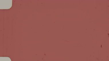 8 mm 'lik kırmızı bir film klipte zengin, solgun bir kırmızı ton, otantik tahıl, organik kusurlar, ince çizikler, dağınık toz parçacıkları ve ince çizgiler sergiliyor.