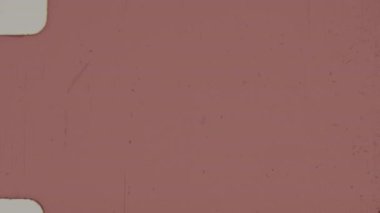 8 mm 'lik kırmızı bir filmden alınan bu çerçeve, 8 mm' lik formatın yuvarlak kenarlı özellikleriyle belirgin tahıl ve toz lekeleri gibi ince kusurlar sergiliyor.