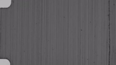 Sayısız çizik, toz zerrecikleri ve yüzey kusurlarıyla ağır bir şekilde yıpranmış, 8 mm 'lik otantik bir film dokusu, dikey çizgilerle donuk gri tonlara sahiptir.