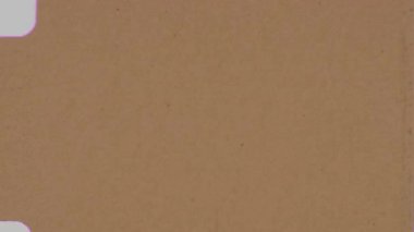 Üzerinde organik koyu kahverengi veya siyah lekeler bulunan dokulu bir klasik kaplama ve sıcak sarı tonlu arka plan patlamaları, ince toz parçacıkları ve kusurları olan 8 mm 'lik bir filmi taklit ediyor.